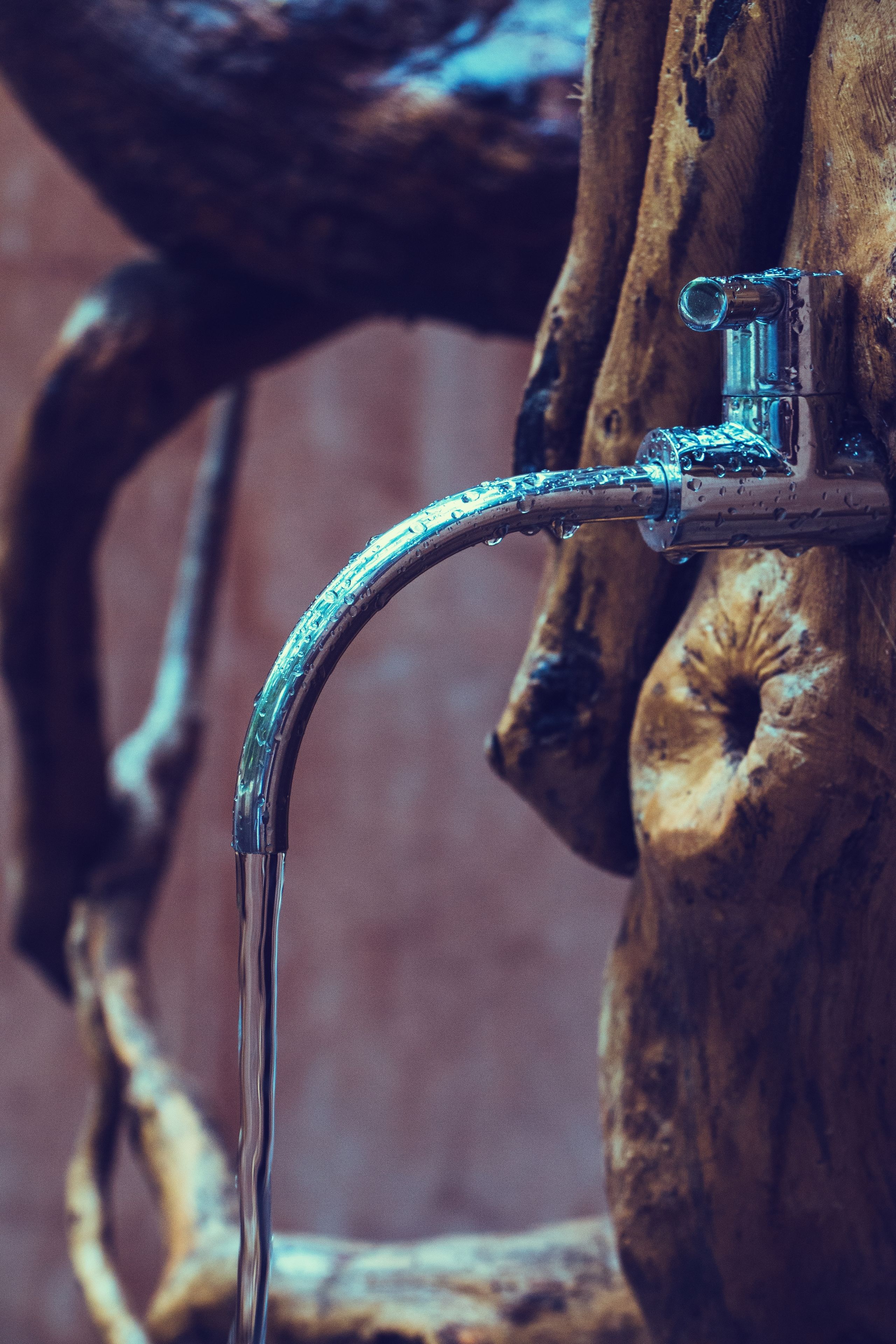 A metal faucet attached to a wooden surface with a visible water stream.