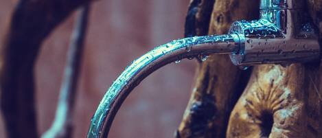 A metal faucet attached to a wooden surface with a visible water stream.