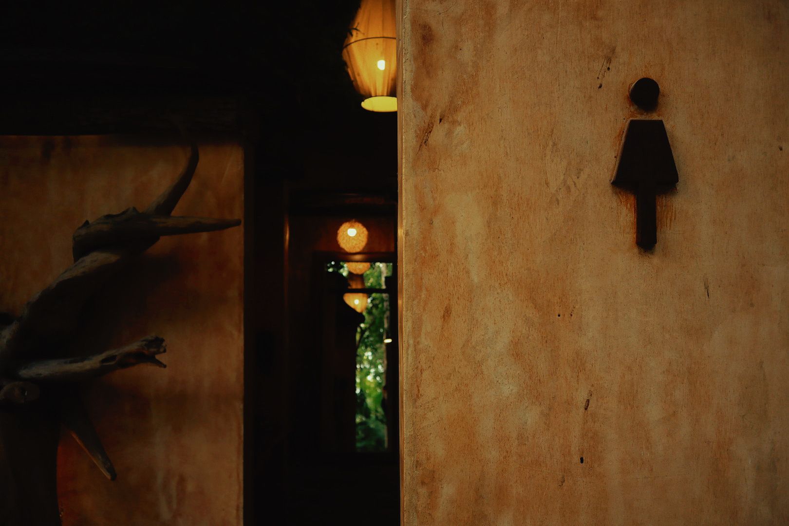 A rustic interior with a wooden wall, a silhouette of a person, and a hanging light fixture.