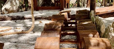 A wooden spiral staircase in a tropical garden setting.