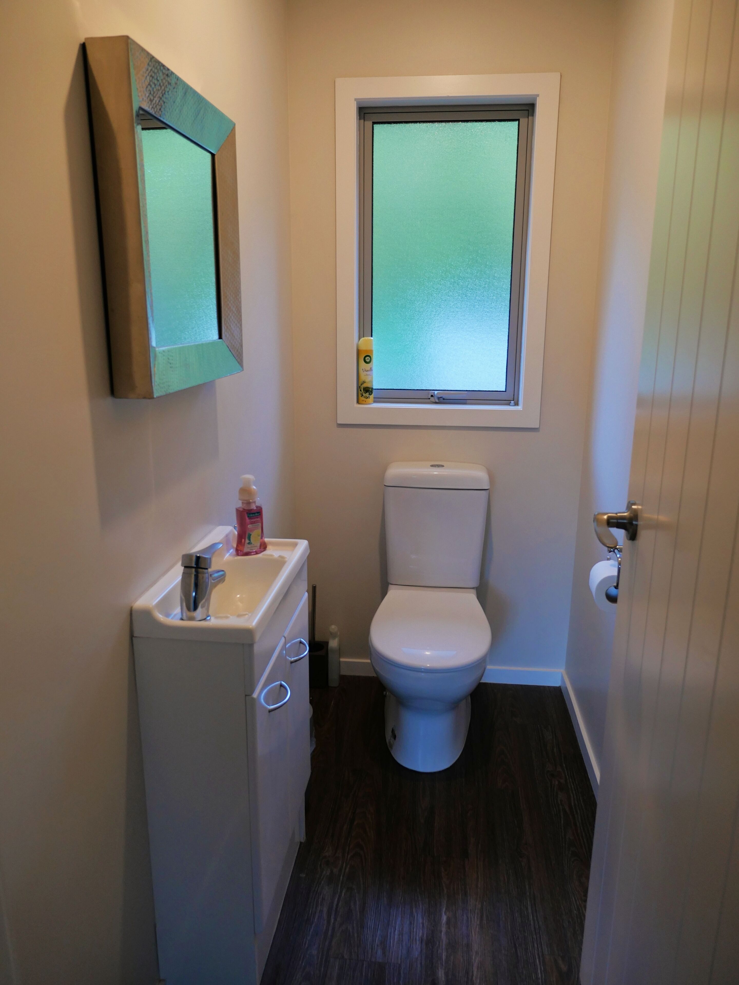 Une petite salle de bain avec des toilettes, un lavabo et un miroir.
