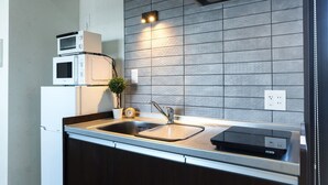 A modern kitchen with a built-in microwave, a sink with a faucet, and a small potted plant. - A9 Haneda Maison Philippe Omori 901 (Tokyo)