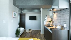 A compact living space with a kitchenette, a bed, a small seating area, and a TV mounted on the wall. - A9 Haneda Maison Philippe Omori 901 (Tokyo)