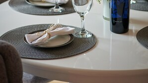 A dining table with a bottle of Korlat Merlot, two wine glasses, a floral centerpiece, and a neatly folded napkin on a placemat. - Apartments Micika - Comfort Studio Apartment with Balcony and Sea View (A2) (Zvekovica)
