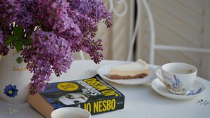 A table with a book, a cup of coffee, a slice of cake, and a vase of purple flowers. - Apartments Micika - Comfort Studio Apartment with Balcony and Sea View (A2) (Zvekovica)