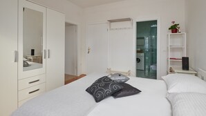 A bedroom with a bed, white wardrobe, and a small bedside table with a plant. - Apartments Micika - Comfort Studio Apartment with Balcony and Sea View (A2) (Zvekovica)