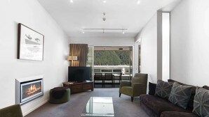 Ein modernes Wohnzimmer mit Kamin, einer Couch, einem Couchtisch und einem Fernseher.