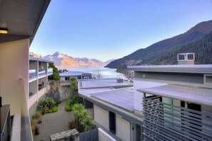 Un edificio moderno con cortile interno, balconi e vista su un lago e montagne.