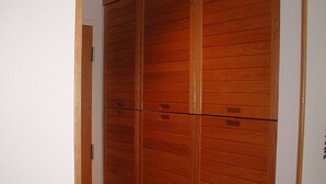 Een gang met een houten garderobe en een deur.