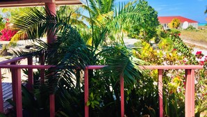 A balcony with a view of a garden and a building with a red roof. - 🌴 Sundial Villas ~ Conch Coastal Calm (Bambarra Beach)