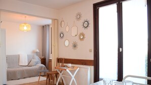 A dining area with a table set for two, a sofa in the background, and decorative wall mirrors. - Cozy apartment with terrace, Wi-Fi, and parking in Évian-les-Bains (Évian-les-Bains)