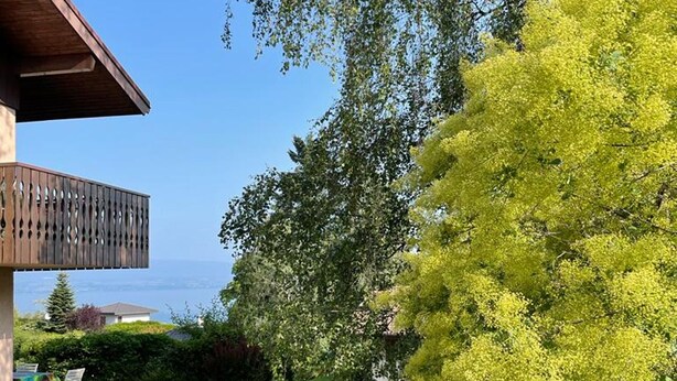 A patio with a table and chairs, a wooden pergola, and a view of the sea. - Cozy apartment with terrace, Wi-Fi, and parking in Évian-les-Bains (Évian-les-Bains)