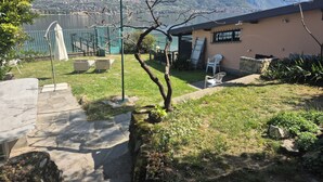A courtyard with a view of mountains, a building with a sloped roof, and outdoor seating. - Lakeside cottage with private garden and pier. Pet-friendly.  (Oliveto Lario)