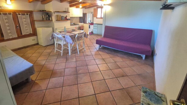 Una cocina con una mesa de comedor, sillas, un sofá y un refrigerador.