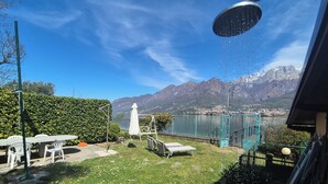 A patio with outdoor furniture, a white umbrella, and a view of mountains. - Lakeside cottage with private garden and pier. Pet-friendly.  (Oliveto Lario)