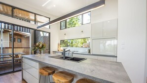 Una cocina moderna con una isla grande, taburetes de bar y vistas al exterior.