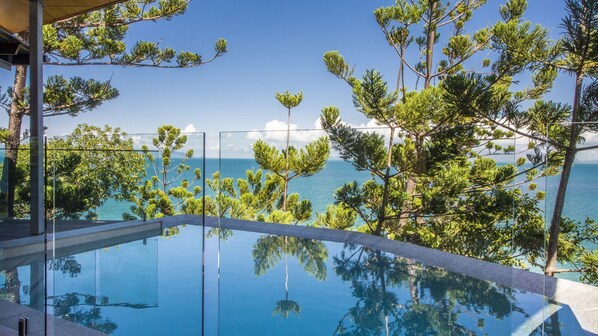 Enjoy a serene infinity pool overlooking the ocean and lush pine trees.
