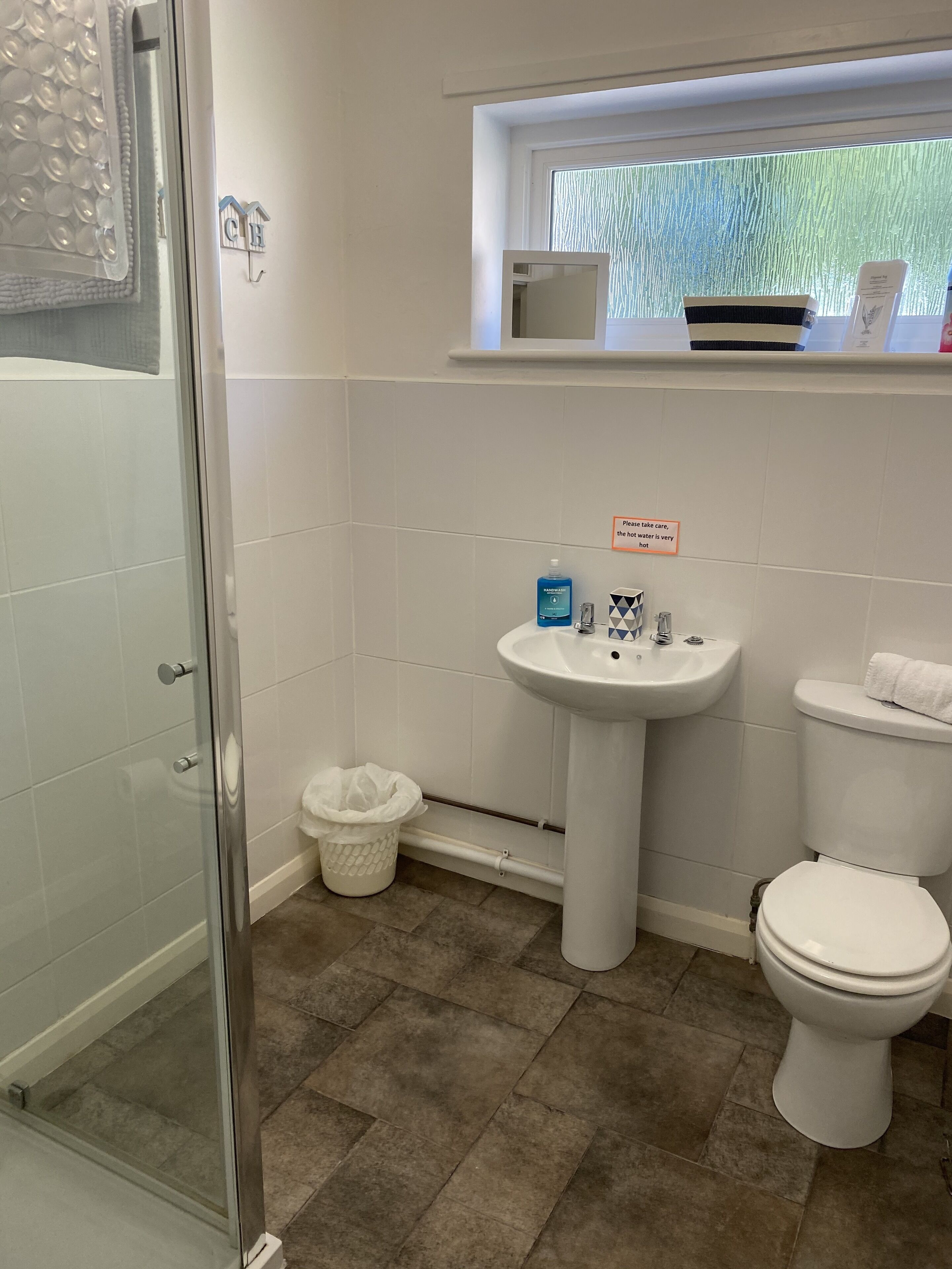 Ein Badezimmer mit Duschkabine aus Glas, einem Waschbecken auf Säule und einer Toilette.