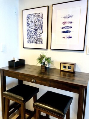 A wooden desk with two black cushioned stools, a small vase with flowers, and two framed artworks on the wall. - B5 Haneda Maison Philippe Omori 502 (Tokyo)