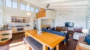 Un amplio espacio de sala con una mesa de comedor de madera, un sofá y un televisor.