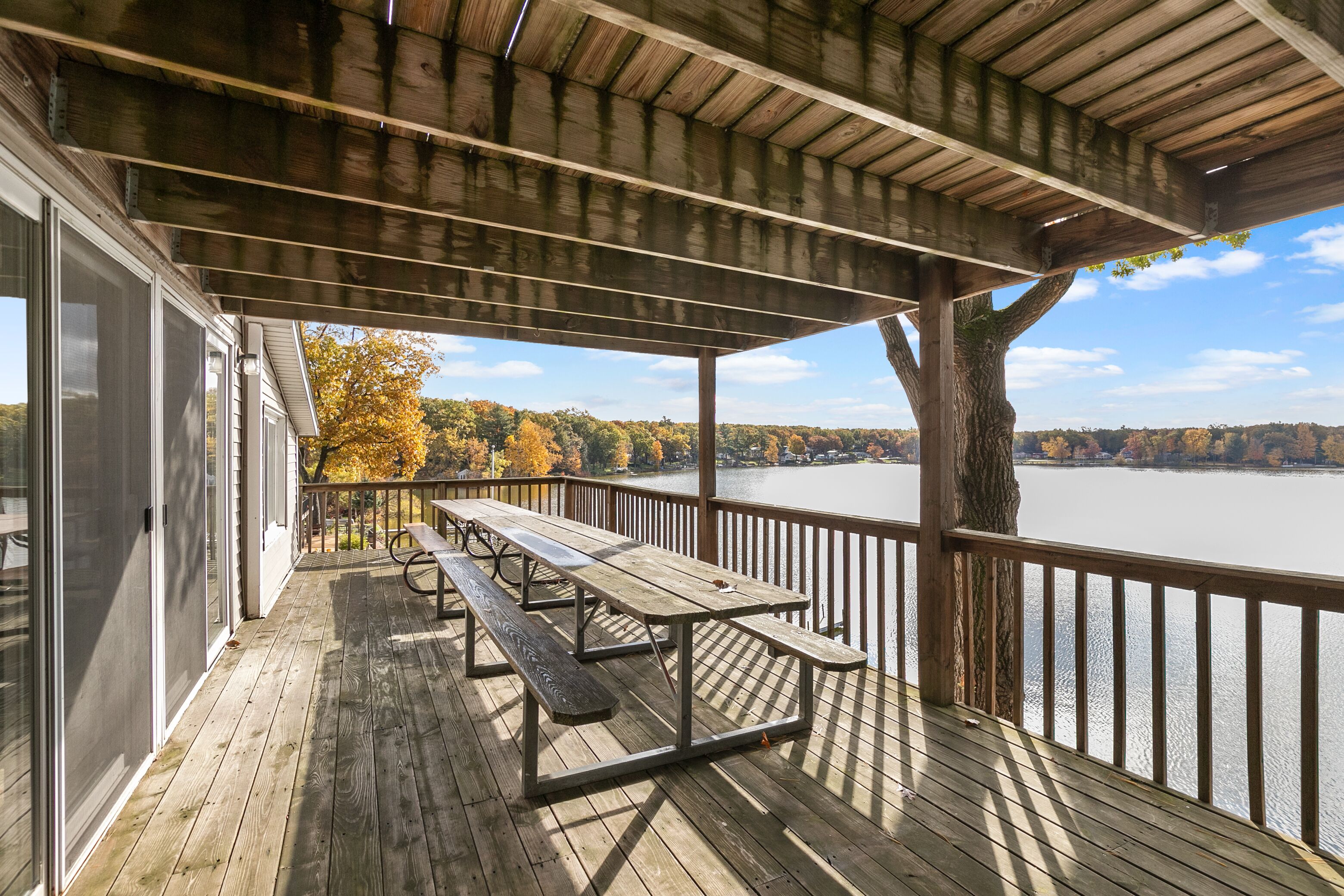 Une terrasse en bois avec des tables de pique-nique donnant sur un lac.