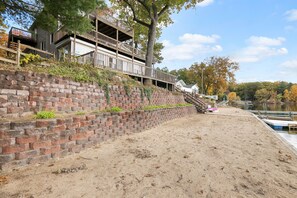 Une propriété située au bord de l’eau, dotée d’un mur de soutènement en briques, d’une terrasse en bois et offrant une vue sur le lac.