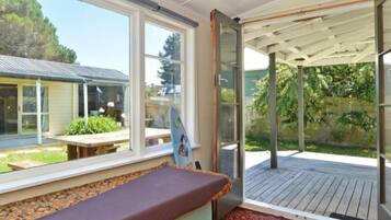 A room with a bed, a window, and a view of a house and garden.