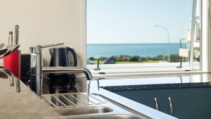 Une cuisine dotée d’un évier en acier inoxydable et d’une fenêtre donnant sur la mer.