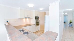 A modern kitchen with white cabinets, a built-in oven, a microwave, and a sink. - Blue Pacific 2 - Yamba (Yamba)