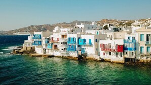 Ein Küstendorf mit weißen Gebäuden, verziert mit blauen und roten Akzenten, am Meer gelegen.