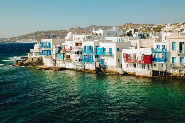 A coastal village with white buildings featuring blue and red accents, situated by the sea.