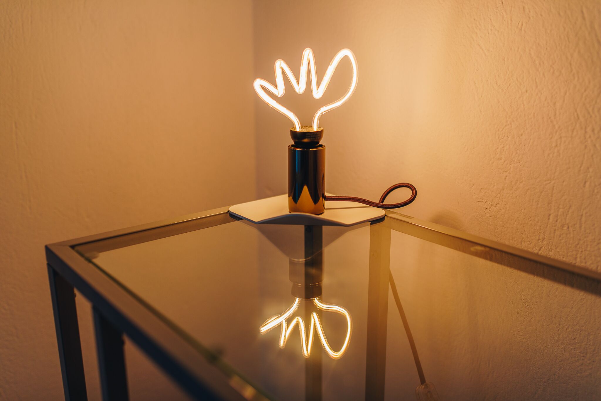 A glass table with a neon light in the shape of a hand on top.
