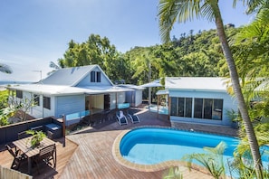 Ein modernes Haus mit Pool, Terrasse und Sitzgelegenheiten im Freien.