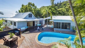 Ein modernes Haus mit Pool, Terrasse und Sitzgelegenheiten im Freien.
