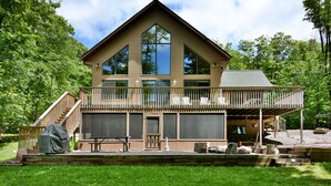 A two-story log cabin with a balcony, large windows, and a deck area.