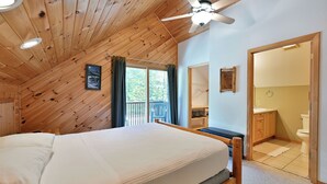 A bedroom with a wooden ceiling, a bed, a ceiling fan, and a view of the outside.