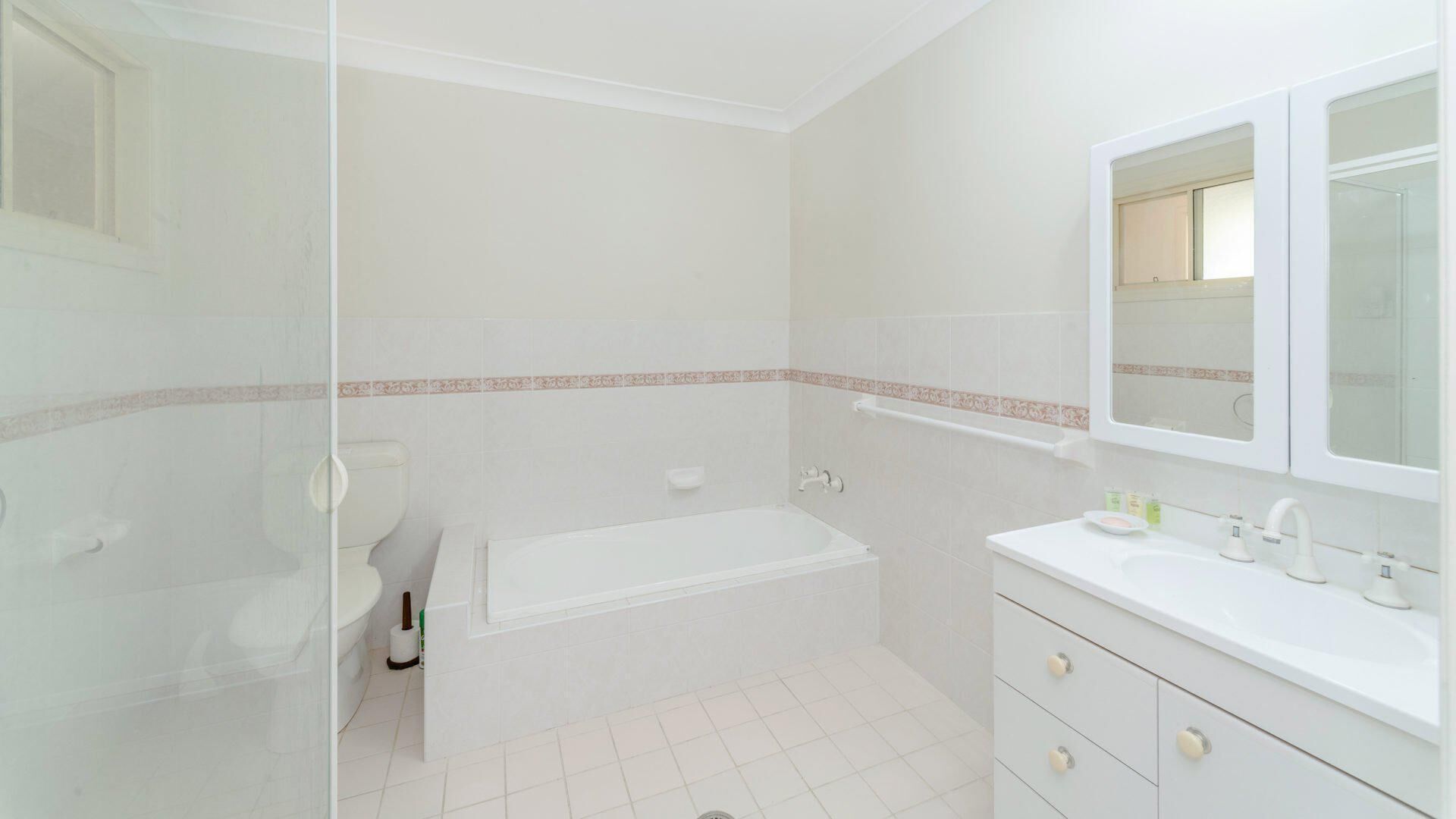 A bathroom with a toilet, bathtub, and a sink with a mirror above it.