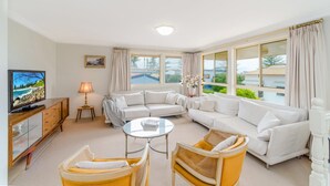 Ein Wohnzimmer mit Fernseher, Sofa, Sesseln und Couchtisch.