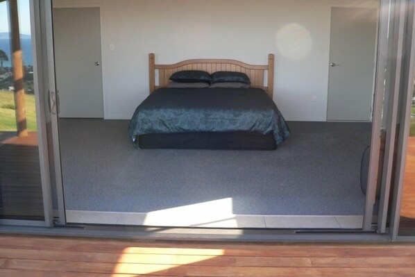 Un dormitorio con cama, una puerta y vistas al exterior.