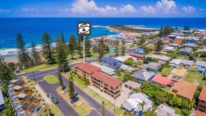 An aerial view of a coastal residential area with houses, a road, and a beach. - Flinders Lodge - an idyllic holiday rental (Yamba)