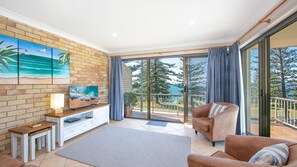 Relax in this inviting living room with a flat-screen TV, comfortable sofa, and stunning views of the lush green landscape.