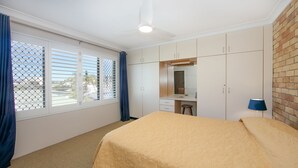 A bedroom with a bed, a desk, and a wardrobe. - Flinders Lodge - an idyllic holiday rental (Yamba)