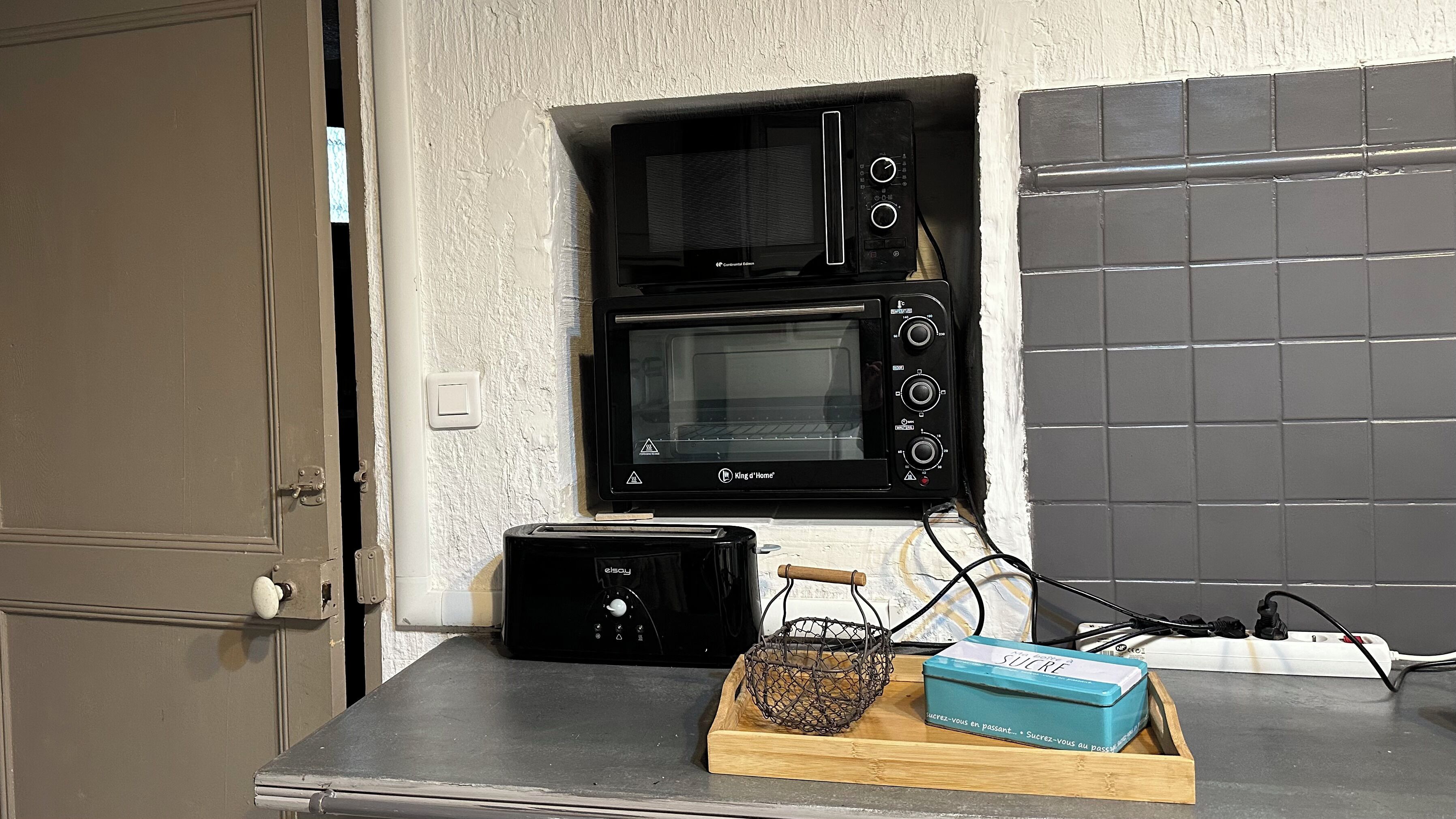 A kitchen with a microwave, toaster, and a blue box on the counter.