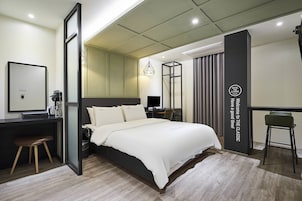 Una habitación de hotel moderna con una cama grande, un escritorio, una silla y un espejo.