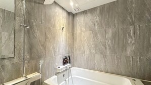 Une salle de bain moderne équipée d’une baignoire, d’une douche et d’un porte-serviettes.