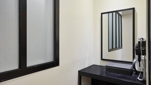 Une chambre d’hôtel avec une grande fenêtre, un miroir, un téléphone et une petite table.