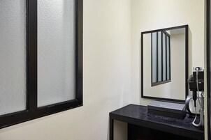 Una habitación de hotel con un ventanal grande, un espejo, un teléfono y una pequeña mesa.