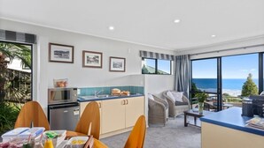 Une chambre moderne dotée d’une cuisine, d’un coin repas et d’un balcon offrant une vue sur la mer.