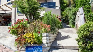 Un immeuble résidentiel doté d’un jardin bien entretenu, d’une enseigne indiquant « Ohoppe Heights » et d’une boîte aux lettres portant le numéro « B2B ».