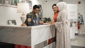 En receptionsdisk med indrammede portrætter, en lampe og et skilt, der tilbyder kundeservice.